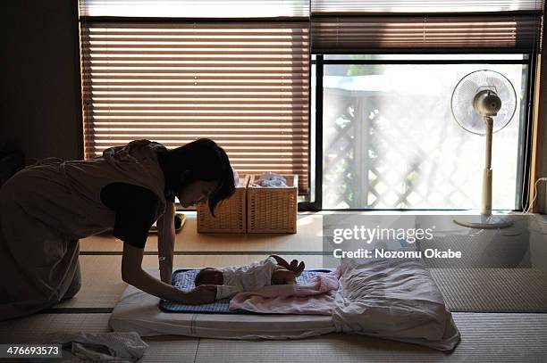 mother watches over her sleeping baby - electric fan ストックフォトと画像