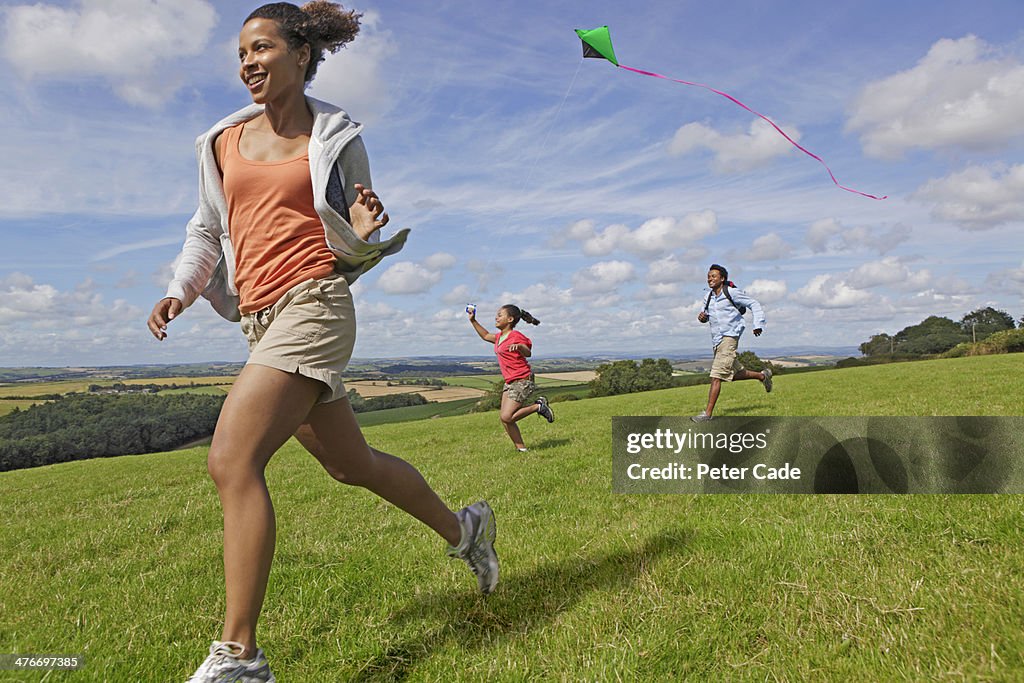 Family running in field with kite in summer