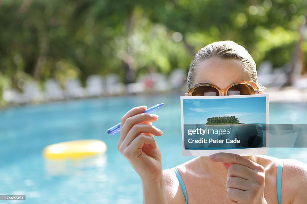 Woman writing postcard by swimming pool