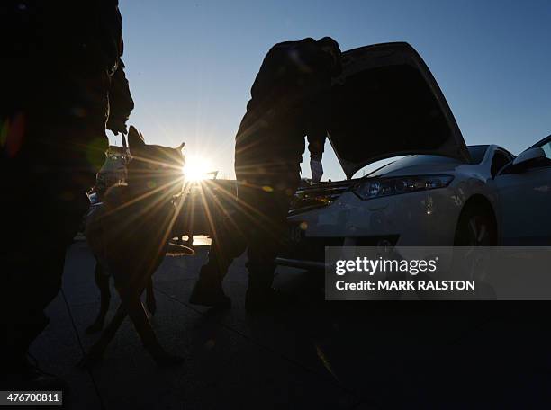 Chinese policeman with his dog checks cars at a security checkpoint before the first session the National People's Congress at the Great Hall of the...