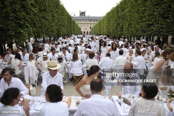 Participants dressed in white enjoy their meal during a "Diner en Blanc" , at the gardens of the Palais-Royal in Paris on June 11, 2015. The "Diner...