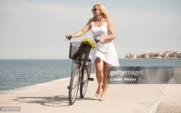 ältere frau reiten fahrrad - blonde long legs stock-fotos und bilder