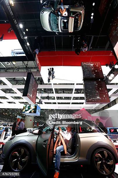 Visitor sits inside an Opel Adam automobile, produced by General Motors Co. , as it stands on display at the company's stand on the opening day of...