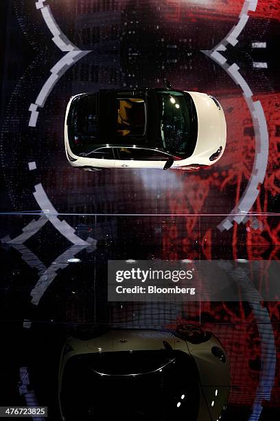 An Opel Adam automobile, produced by General Motors Co. , hangs on the wall of the company's stand on the opening day of the 84th Geneva...