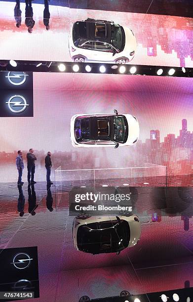 Visitors look at an Opel Adam automobile, produced by General Motors Co. , center, mounted on the wall of the company's stand on day two of the 84th...