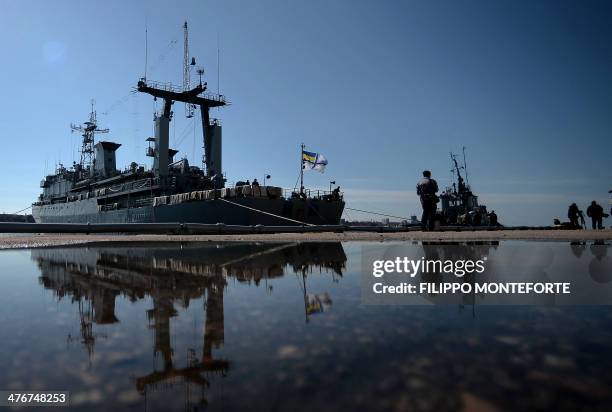 Ukrainian soldiers onboard the navy ship Slavutich stand guard as they look out at Russian forces patrolling in the harbor of the Ukrainian city of...