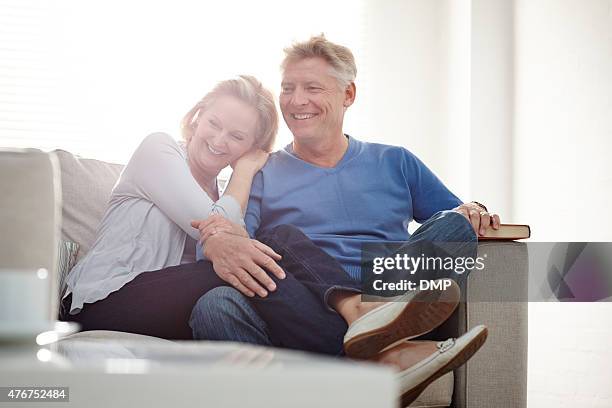 heureux couple d'âge mûr assis ensemble sur un canapé - adulte dâge mûr photos et images de collection