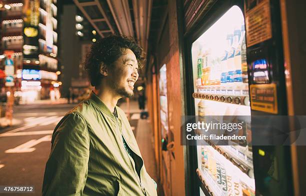 young japanese man buys drink from the machine - vending machine stock pictures, royalty-free photos & images