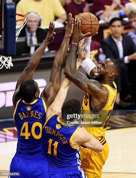 LeBron James of the Cleveland Cavaliers goes up against Klay Thompson and Harrison Barnes of the Golden State Warriors in the first quarter during...