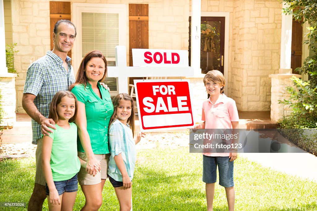 Family with "house for sale, sold" real estate sign. Summer.