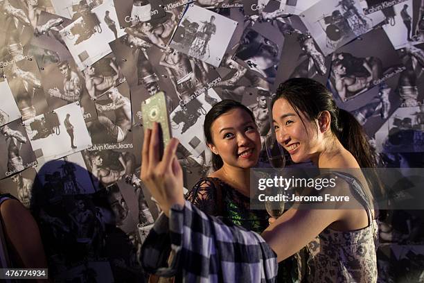 Guests take selfies in front of decorated wall with Justin Bieber photos at the Calvin Klein Jeans music event in Hong Kong with special appearance...