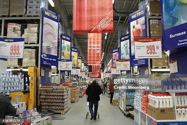 Customer pushes a shopping cart along a food aisle inside a Metro AG Cash & Carry supermarket store in Moscow, Russia, on Wednesday, March 5, 2014....