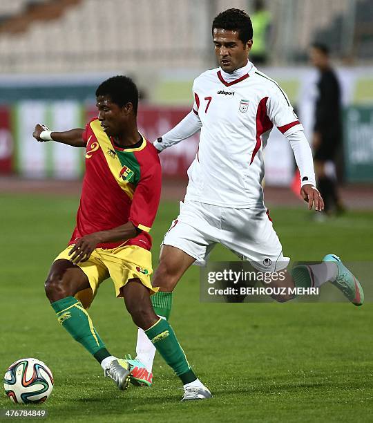 Iran's Masoud Shojaei fights for the ball with Babacar Camara of Guinea during their international friendly football match at the Azadi Stadium in...