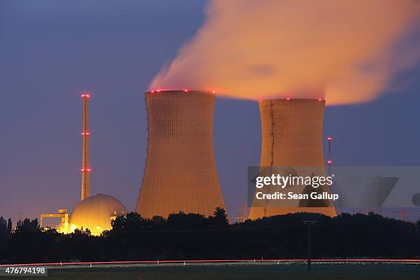 Passing cars leave a streak of light as steam rises from the cooling towers of the Grafenrheinfeld nuclear power plant at night on June 11, 2015 near...