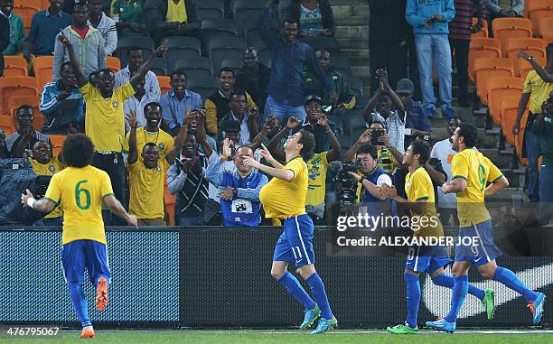 Brazil's midfielder Oscar celebrates with the ball under his jersey after scoring a goal during a friendly football match between South Africa and...