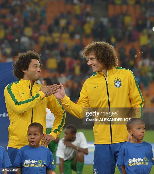Brazil's midfielder Willian taps hands with Brazil's defender David Luiz prior to a friendly football match between South Africa and Brazil at Soccer...