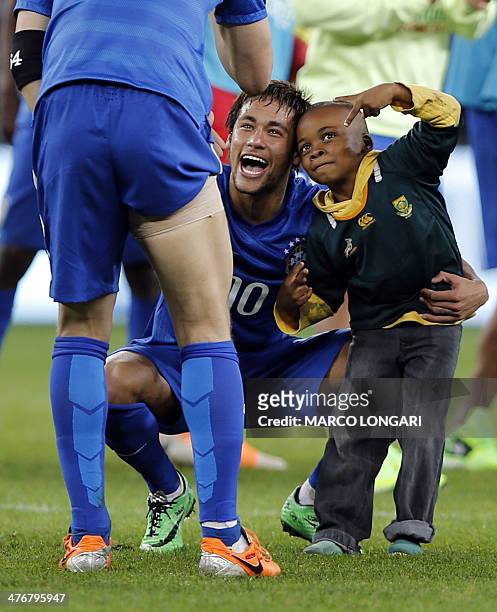 South African boy who invaded the pitch jokes with Brazil's forward Neymar at the end of a friendly football match between South Africa and Brazil at...