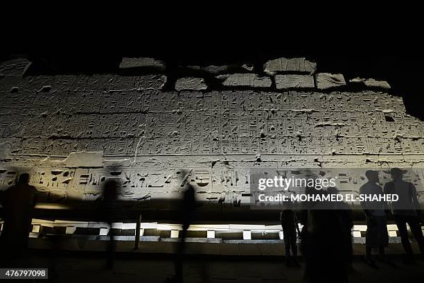 Tourists walk past hieroglyphics at Karnak temple in Luxor, a town 700 kilometres south of the Egyptian capital, Cairo, in the evening of June 11,...