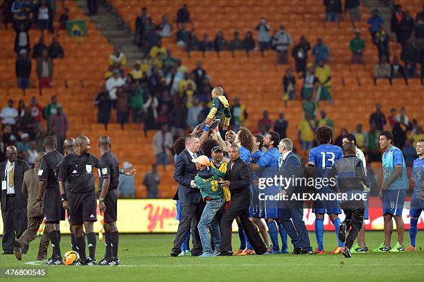 Security prevent a young South African supporter from approaching Brazilian players, as one of them plays with a younger one, at the end of a...