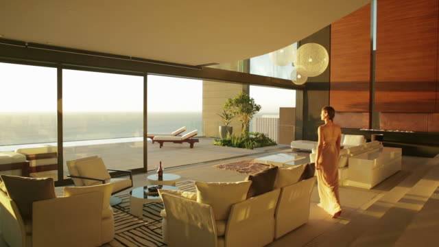 Woman walking through luxury living room to patio overlooking ocean