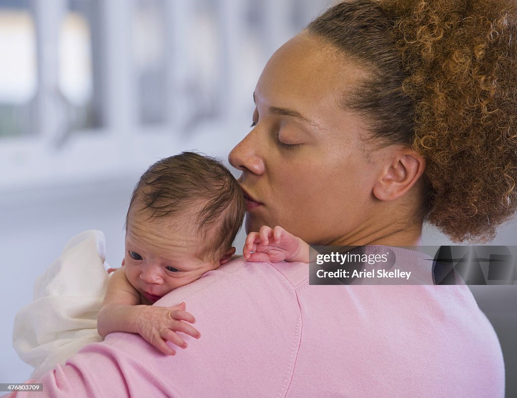 Mixed race mother holding newborn baby
