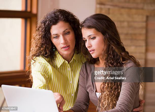 mixed race mother and daughter using laptop together - mixed race family stock-fotos und bilder