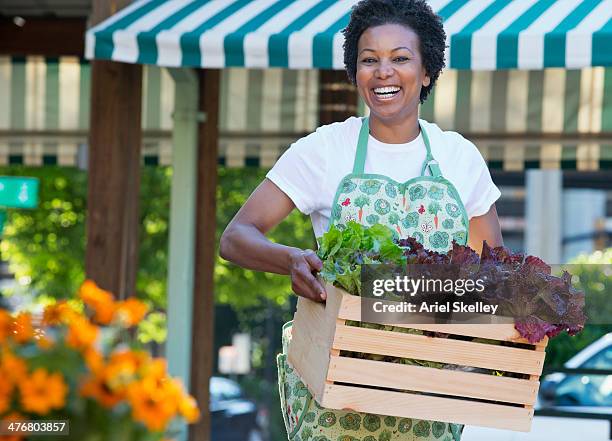 black grocer carrying crate of lettuce - groenteboer stockfoto's en -beelden