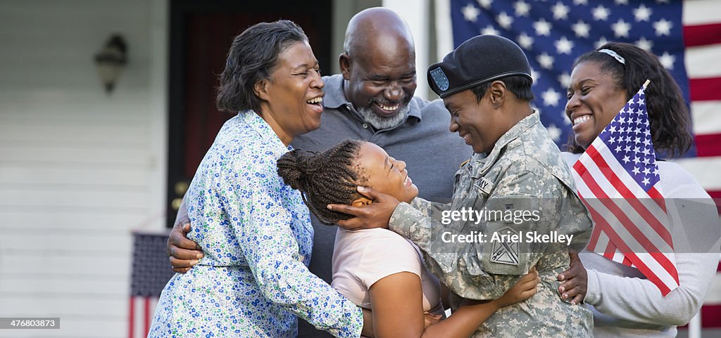 Black family greeting returning female soldier