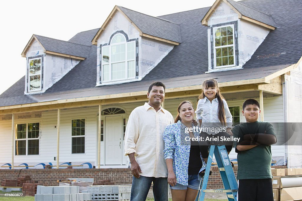 Hispanic family smiling outside house under construction