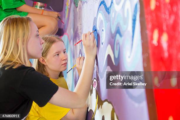 caucasian women painting mural - ferienlager stock-fotos und bilder