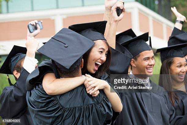 graduates hugging outdoors - university students celebrate their graduation fotografías e imágenes de stock