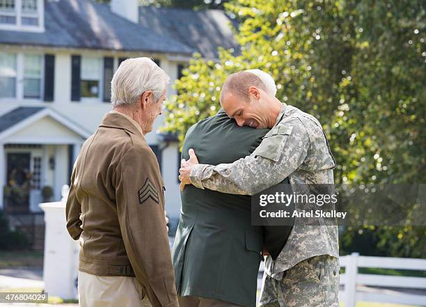 caucasian multi-generation soldiers hugging outdoors - homecoming stock pictures, royalty-free photos & images