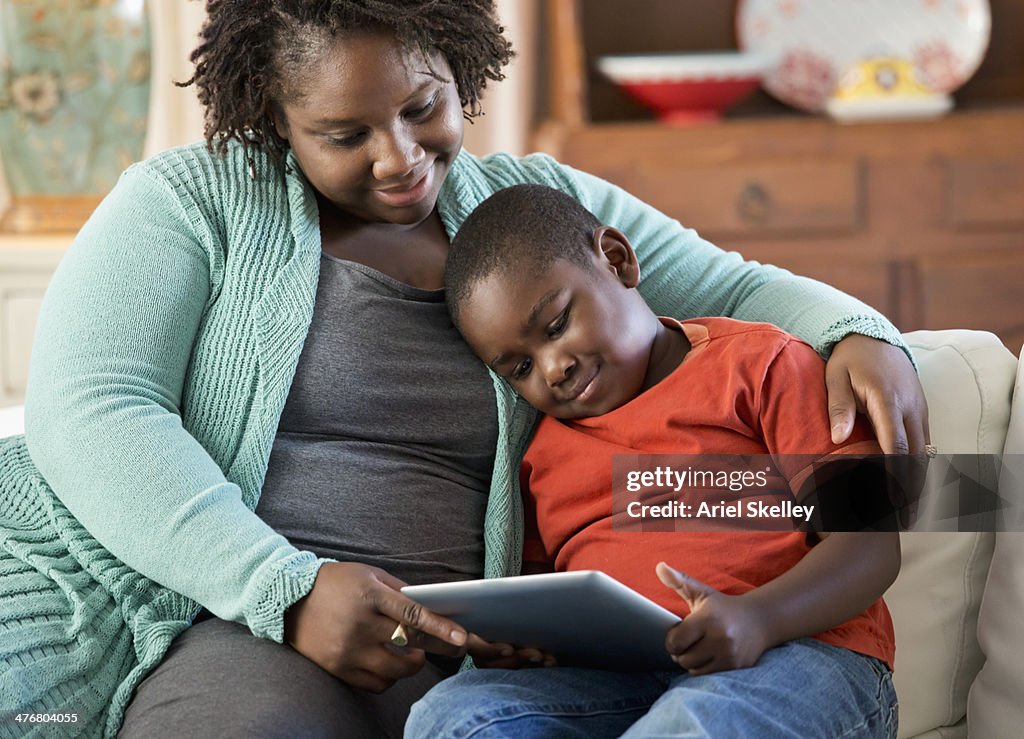 Black mother and son using digital tablet together