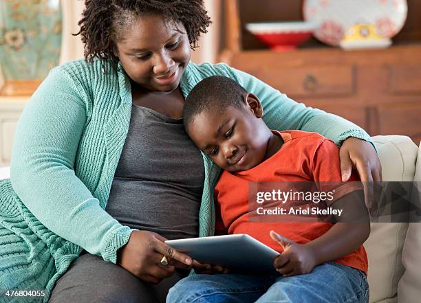 black mother and son using digital tablet together - mother happy reading tablet stock pictures, royalty-free photos & images