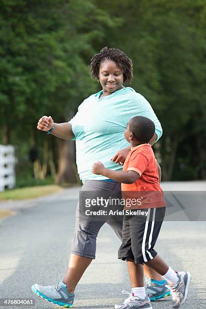 black mother and son walking on road - chubby boy fotografías e imágenes de stock