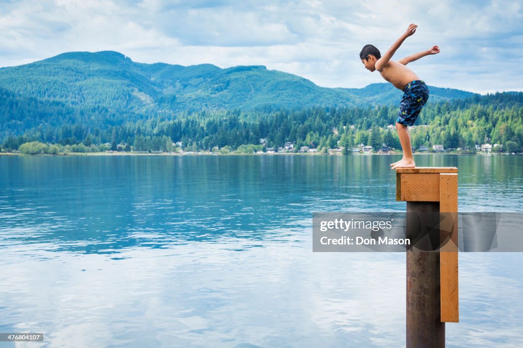 Korean boy jumping off platform into lake