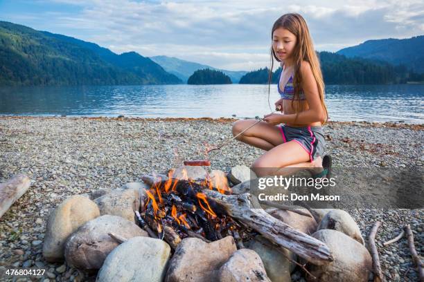 mixed race girl roasting hot dog at campfire - lake whatcom foto e immagini stock