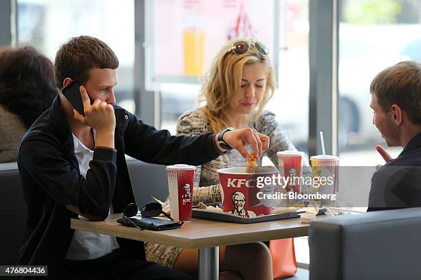 Customer eats fried chicken from a KFC "bucket" in the new 24-hour KFC fast food restaurant, operated by Yum! Brands Inc., in Moscow, Russia, on...