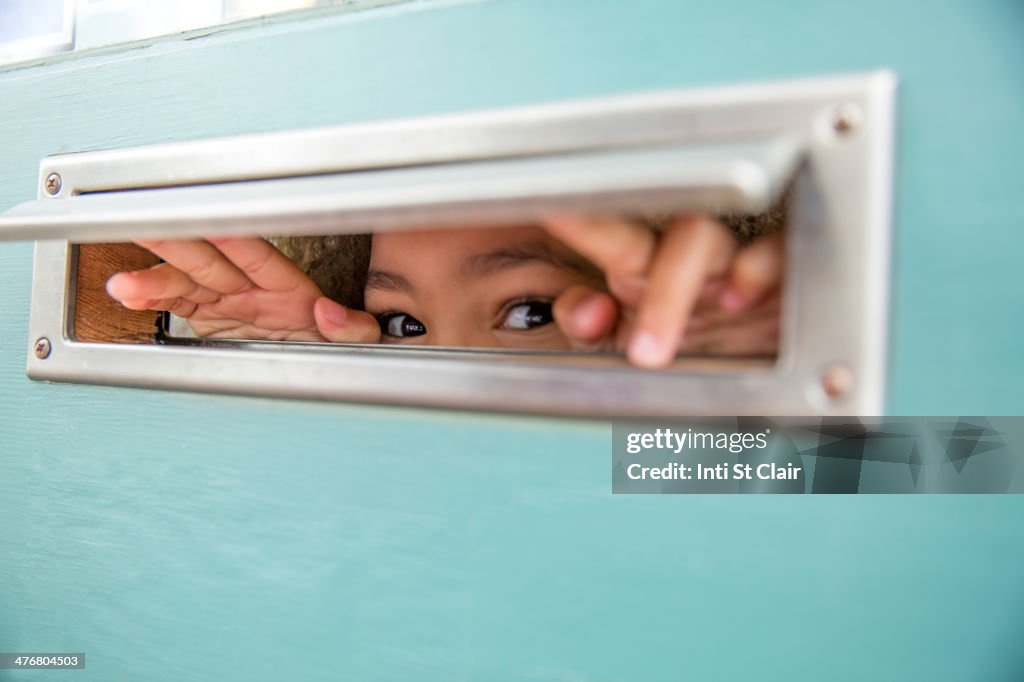 Mixed race girl peeking through mail slot