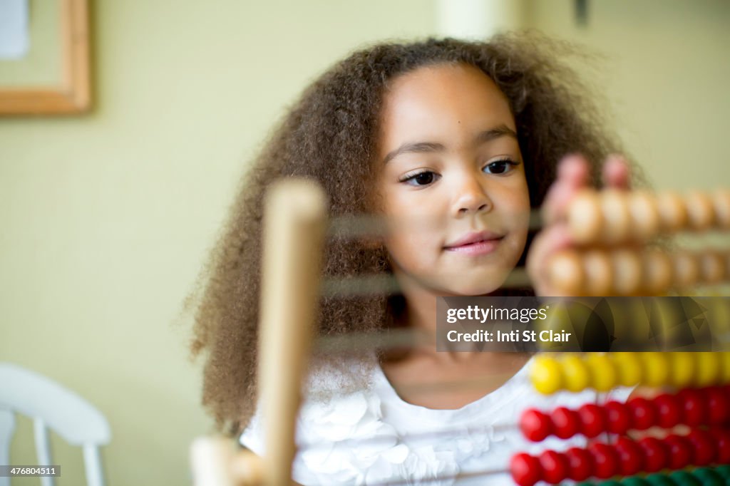 Mixed race girl using abacus