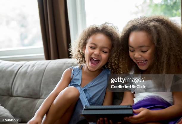 mixed race girls using digital tablet on sofa - free download photo stock pictures, royalty-free photos & images