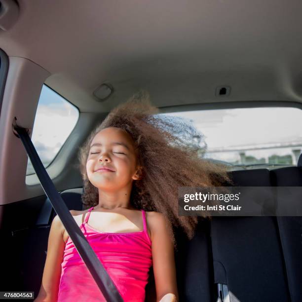 mixed race girl enjoying wind in hair in back seat of car - back seat stock pictures, royalty-free photos & images