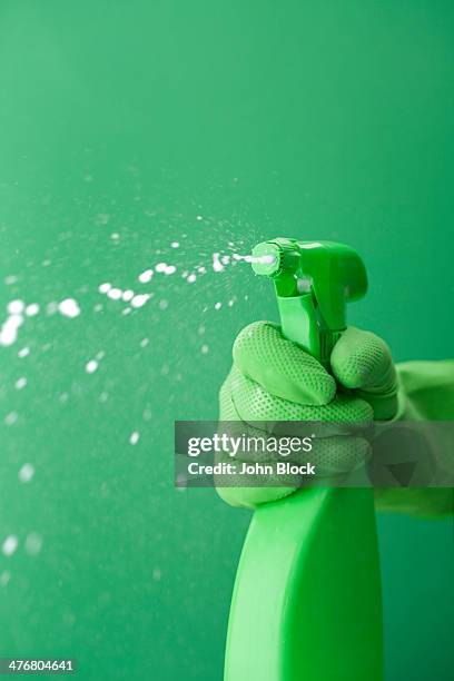 green rubber glove squiring spray bottle - green glove stockfoto's en -beelden