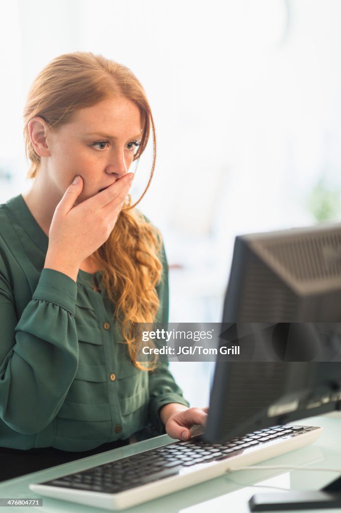 Businesswoman gasping at computer in office