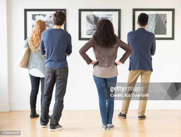 couples admiring art in gallery - back photos et images de collection