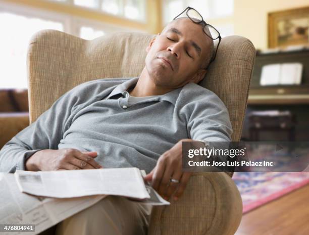 mixed race man sleeping in armchair - nickerchen stock-fotos und bilder