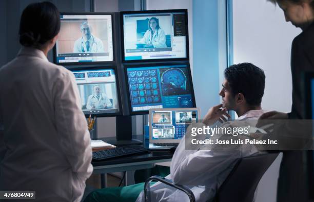 doctors examining x-rays in video conference - medical technology stock-fotos und bilder