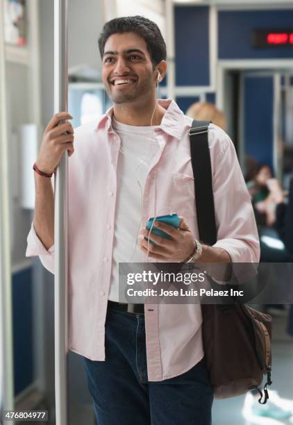 man listening to earphones on subway train - pole positie fotografías e imágenes de stock