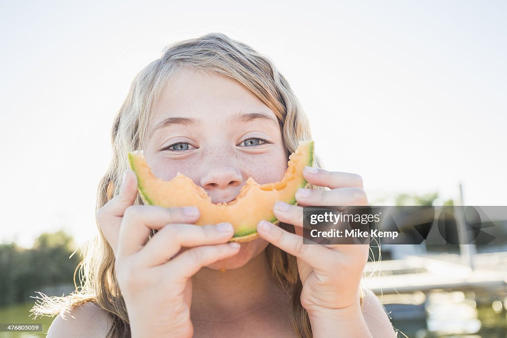 Caucasian girl eating cantaloupe slice