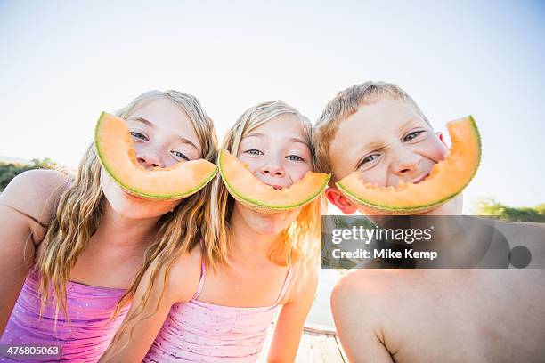 caucasian children eating cantaloupe slices - カンタロープメロン ストックフォトと画像